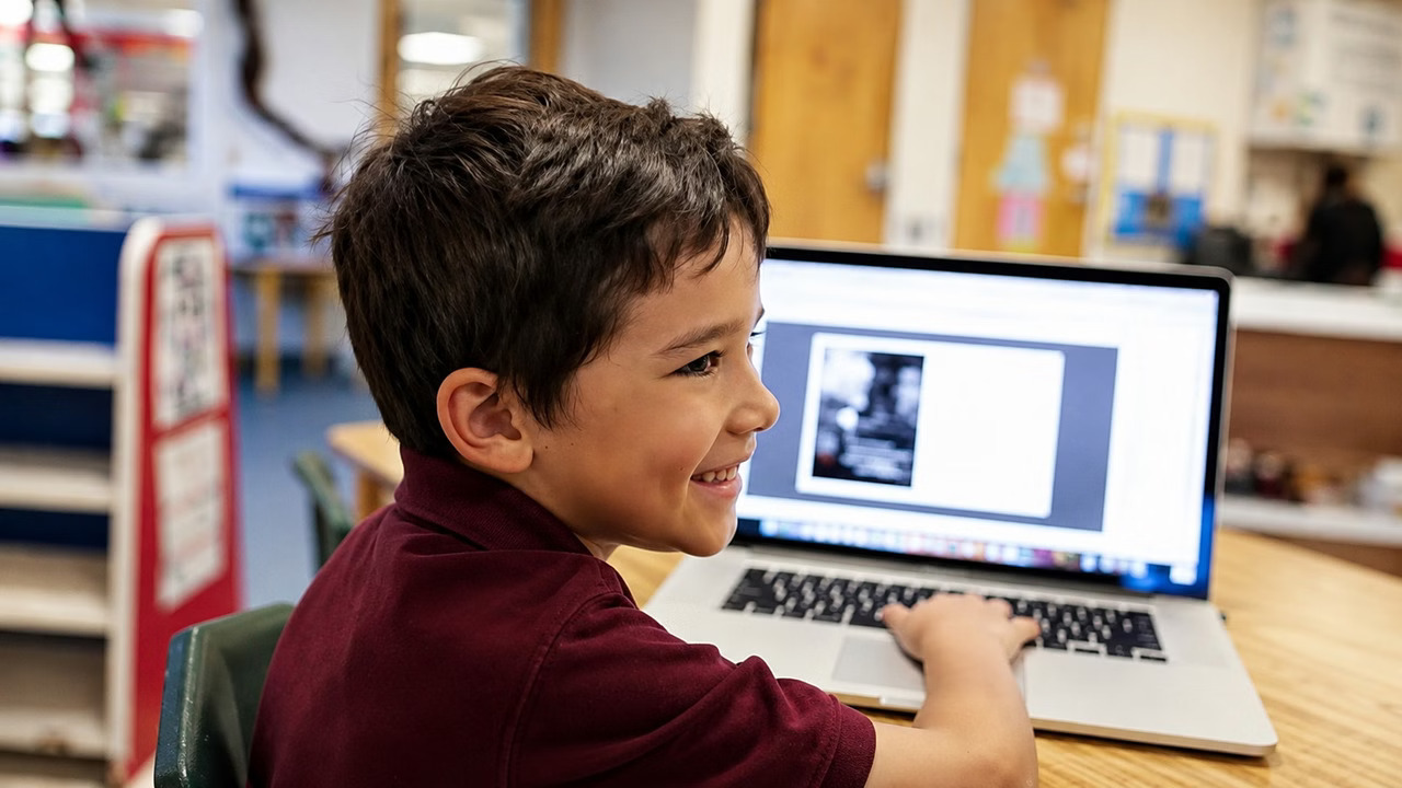 A student smiling while working on a laptop